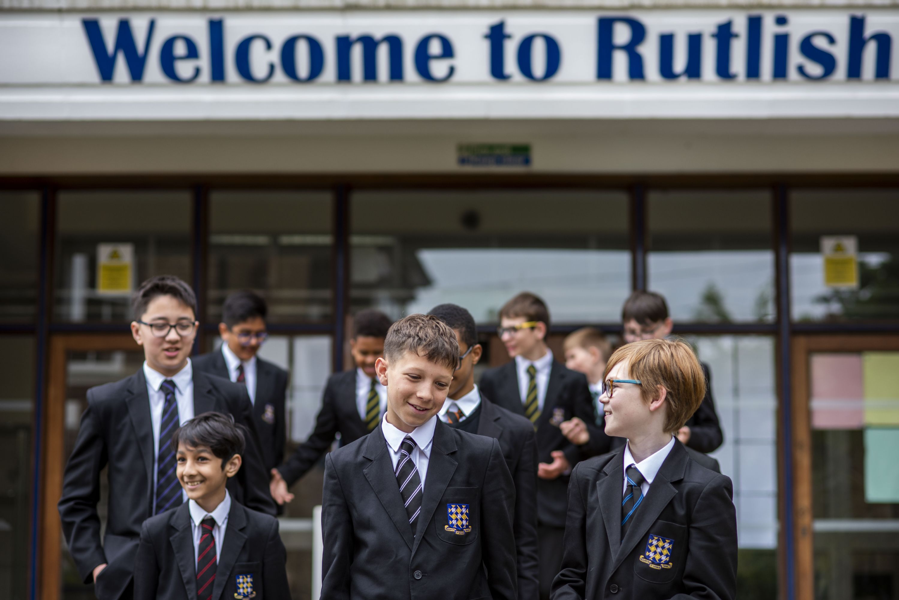Rutlish students standing under the Welcome to Rutlish sign