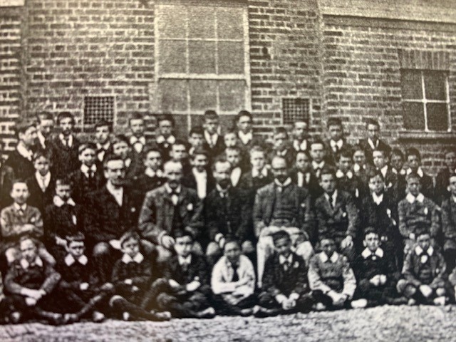an old black and white school photo of staff and students