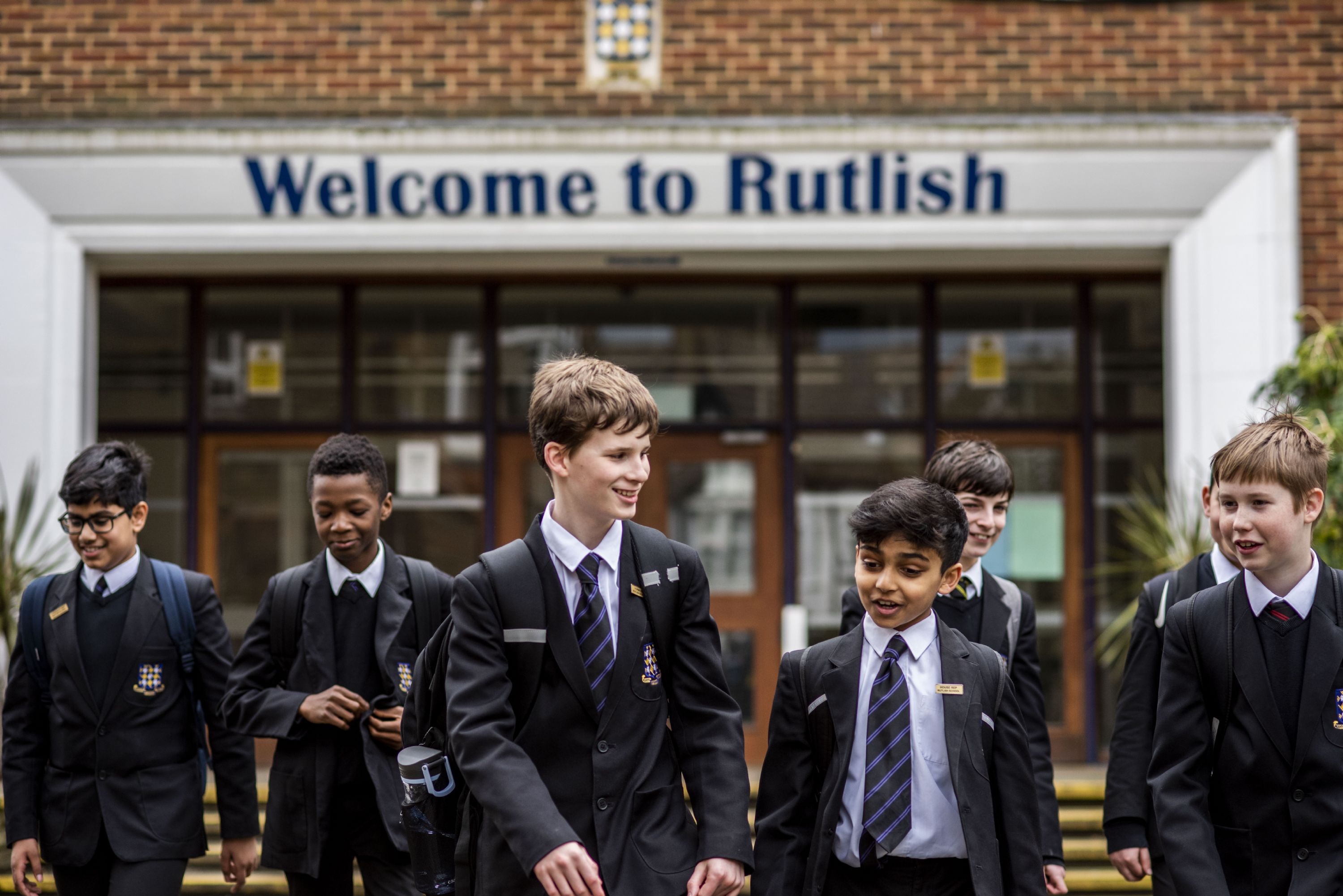 Rutlish students standing under the Welcome to Rutlish sign